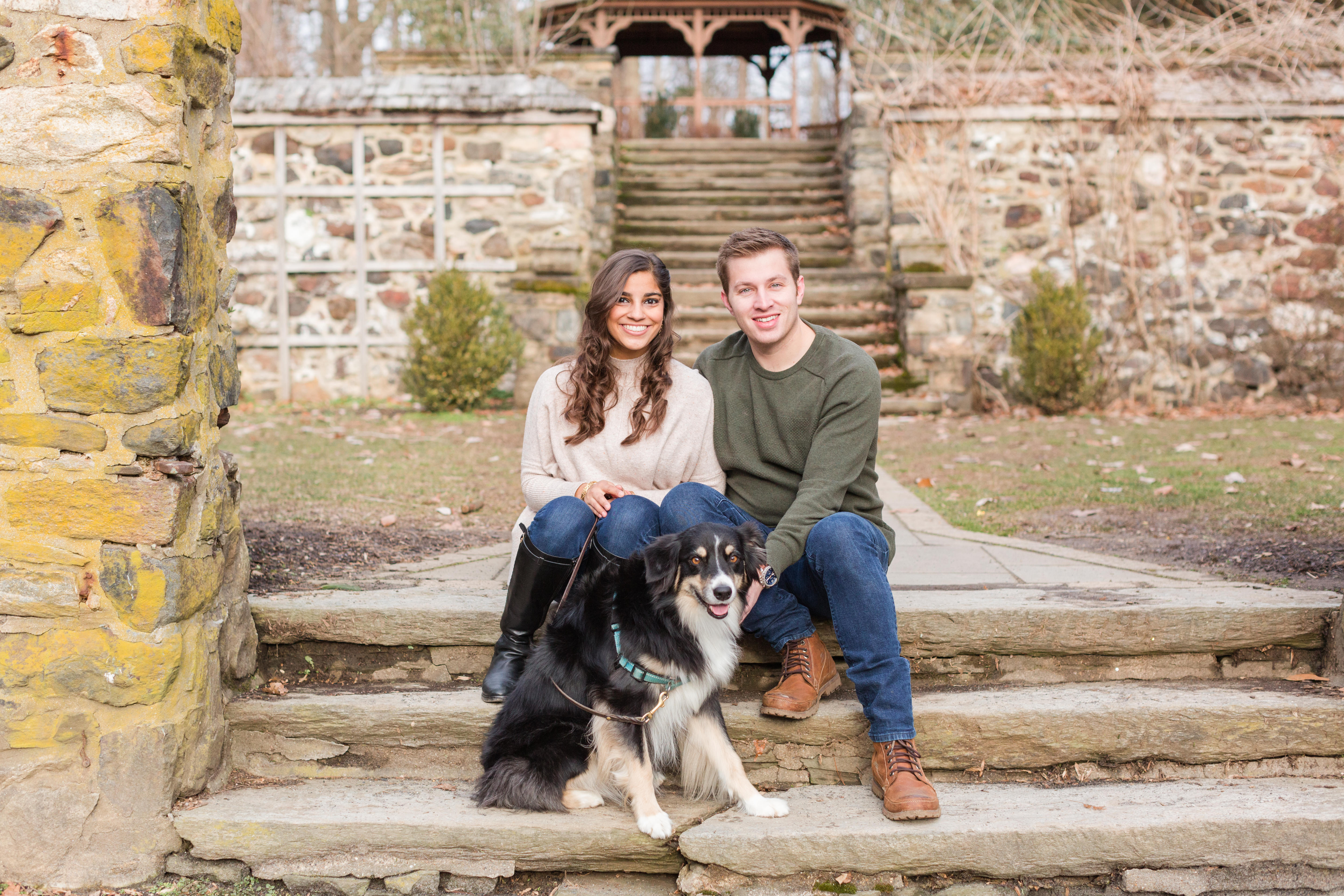 Couple smiles with dog during engagement session