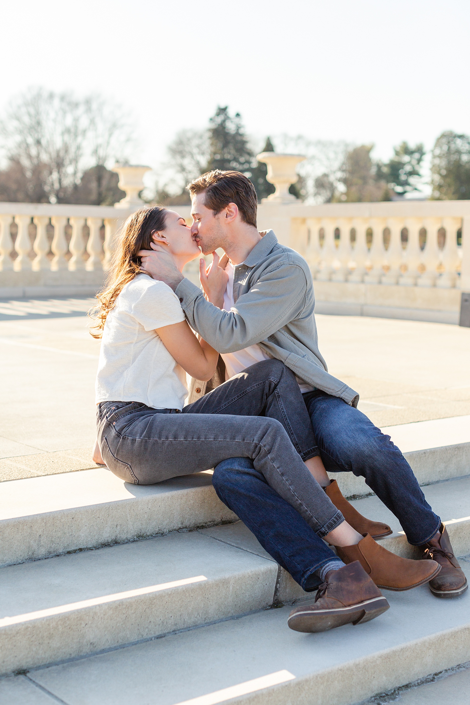 Couple kisses sitting at top of stairs during Longwood Gardens Spring Engagement Session