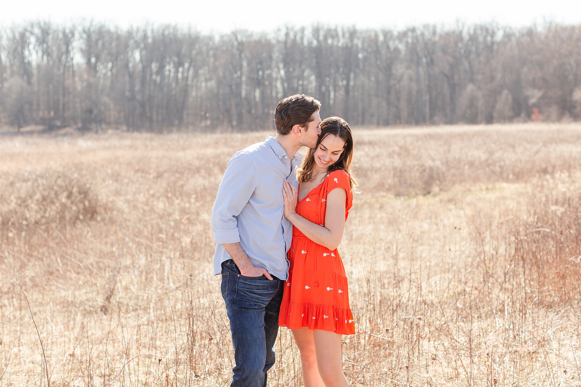 Michael kisses Erica on by tall grass. during Longwood Gardens Spring Engagement Session