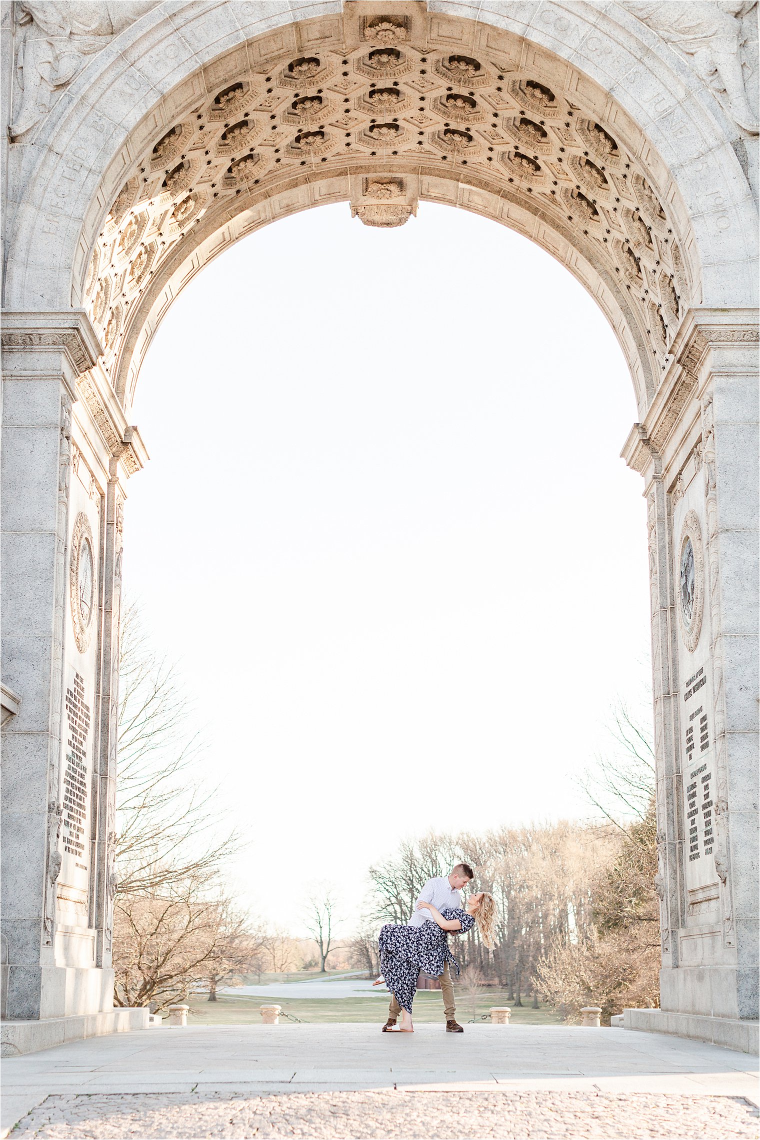Couple kisses under large archway during Valley Forge Engagement Session