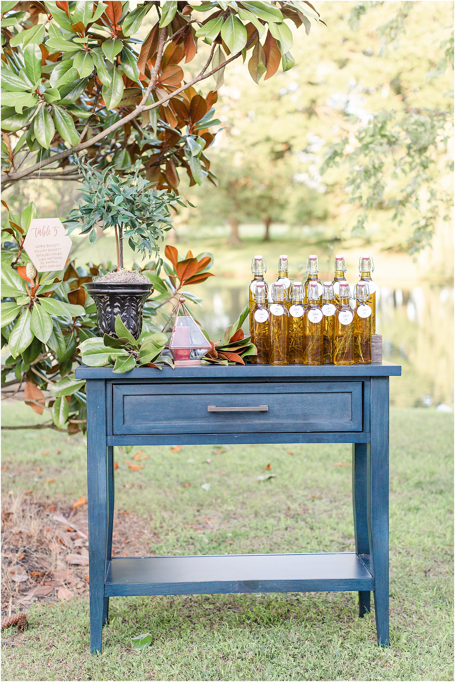 Wedding Favors of bottled olive oil and thyme displayed on blue table 