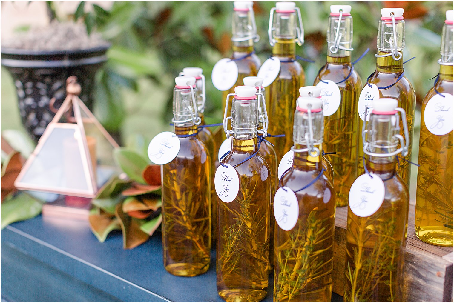 Wedding Favors of bottled olive oil and thyme displayed on blue table 