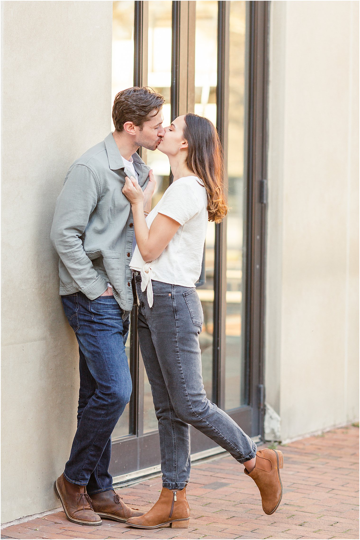 Couple kisses near building during Longwood Gardens Engagement session