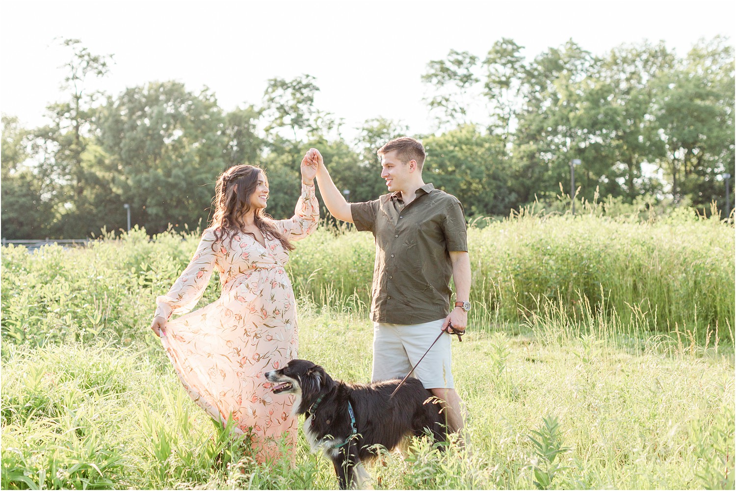 husband and wife twirl in grass with their dog during Bartram’s Garden maternity session by Jocelyn cruz photography