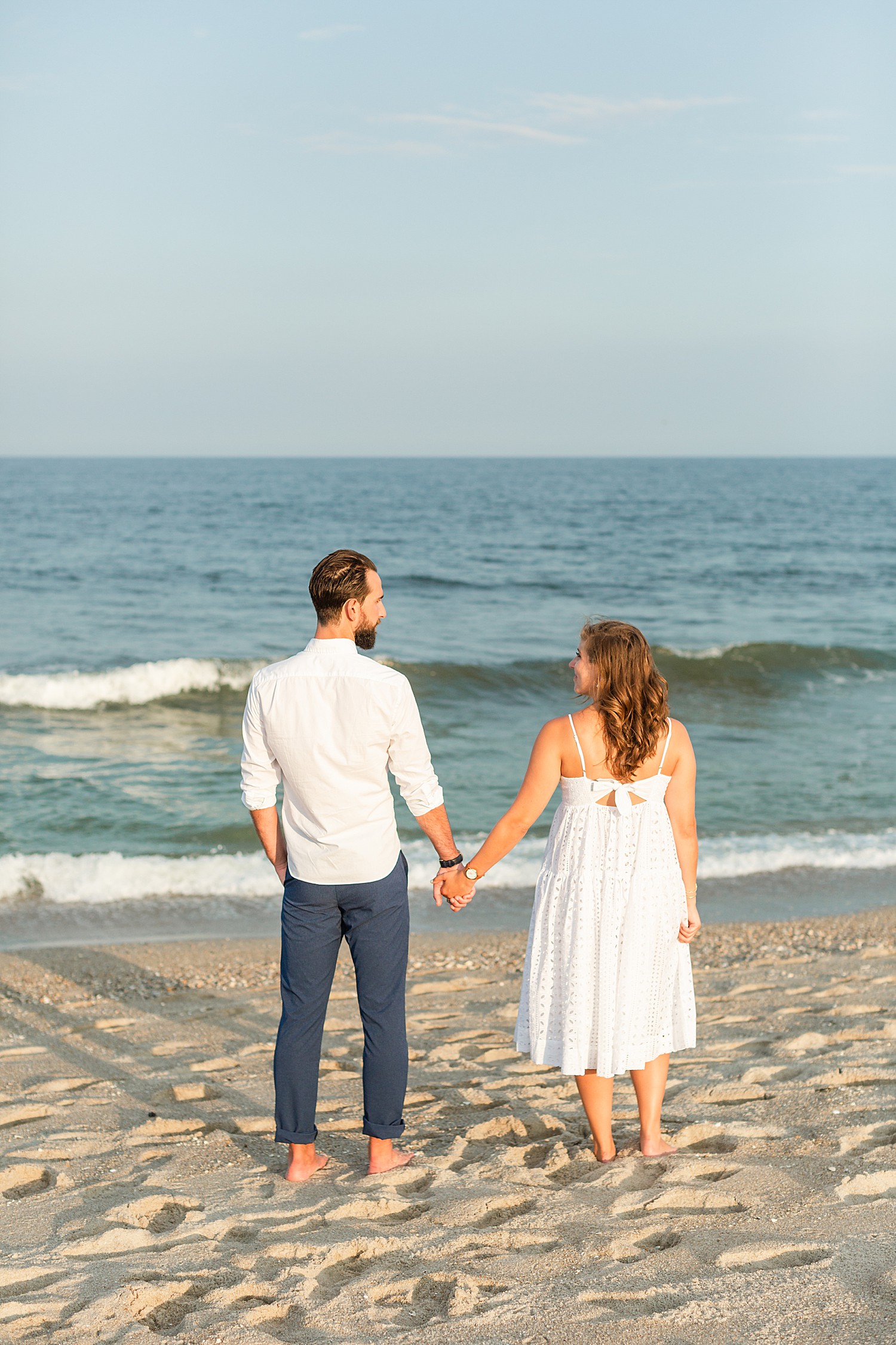 Engaged photos holding hands looking out at ocean