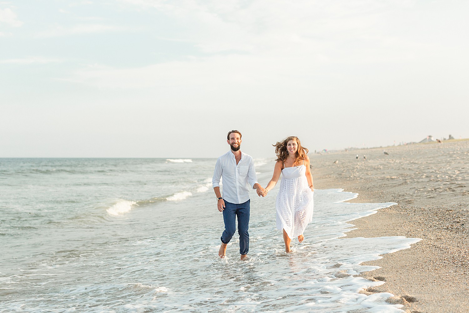 engaged couple run through rolling waves on the beach of Bay Head NJ