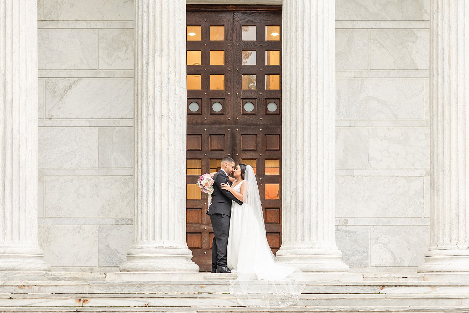 Husband + Wife take wedding portraits at Princeton University at the top of stairs by columns 