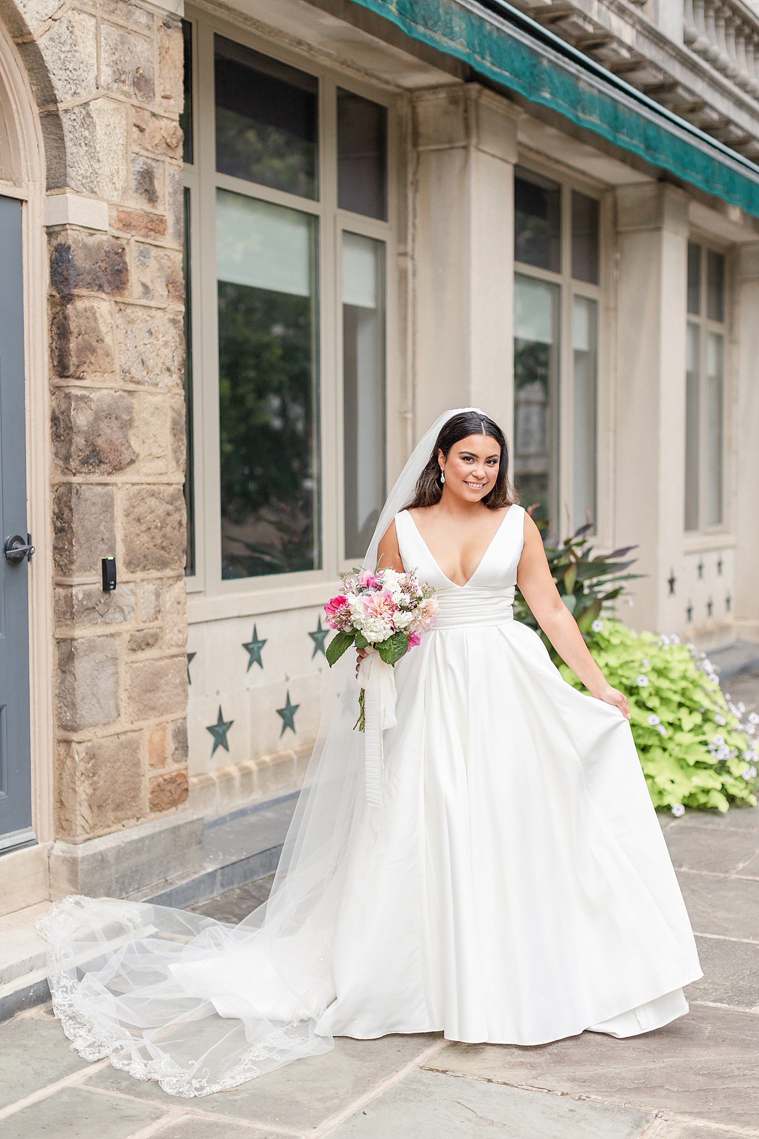 bride holds out wedding dress during wedding portrait