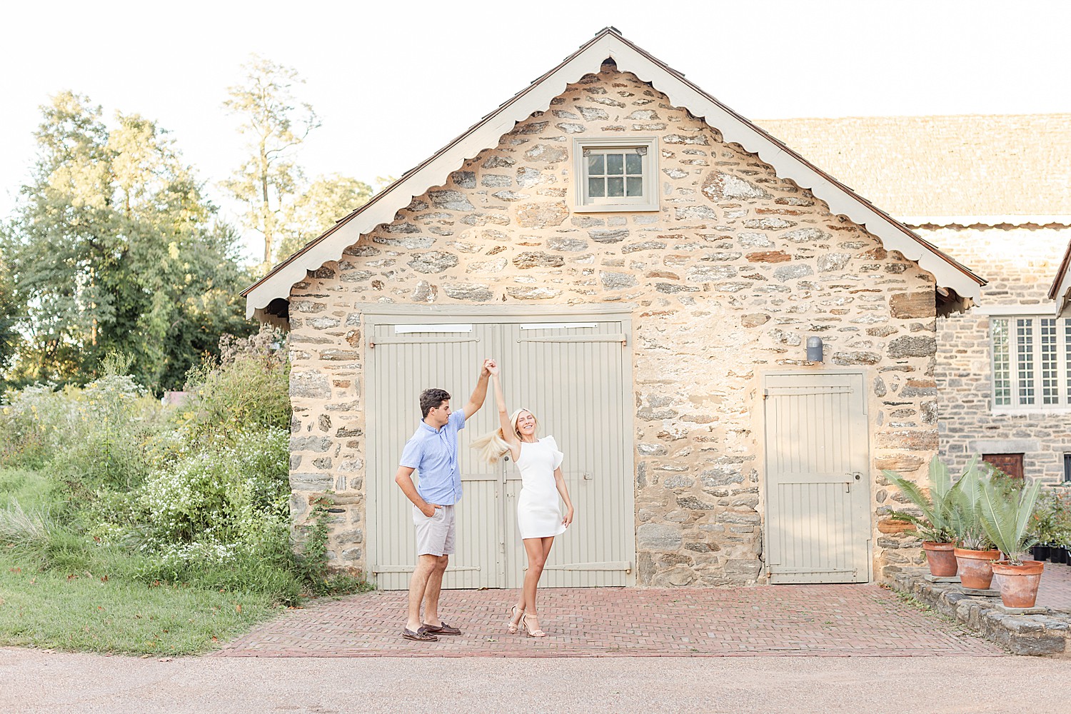 guy spins his fiance around near stone covered building