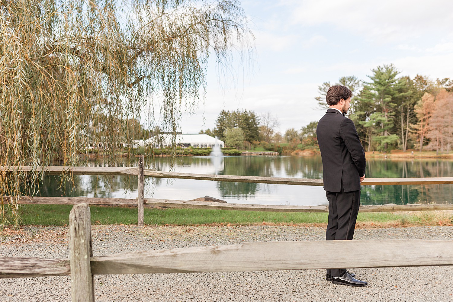 groom standing on path on the other side of the lake waiting for bride 