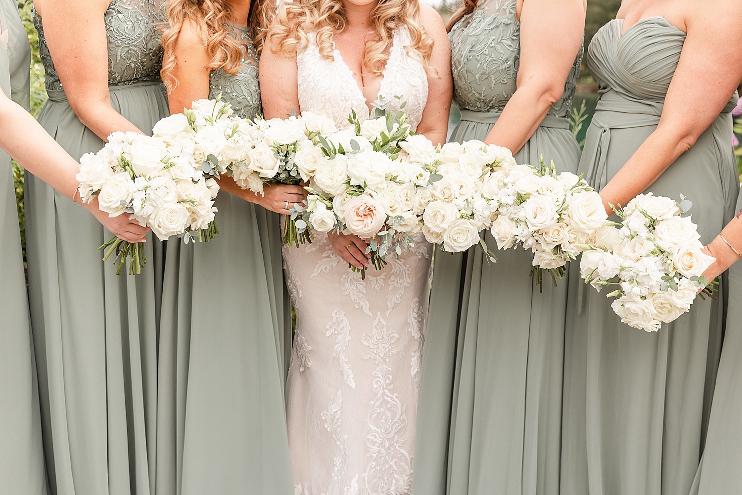 bridesmaids and bride hold out white flower bouquets 
