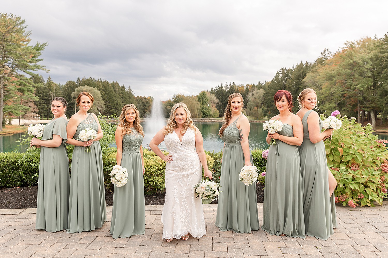 bride in the center with her bridesmaids around her and water fountain in background 
