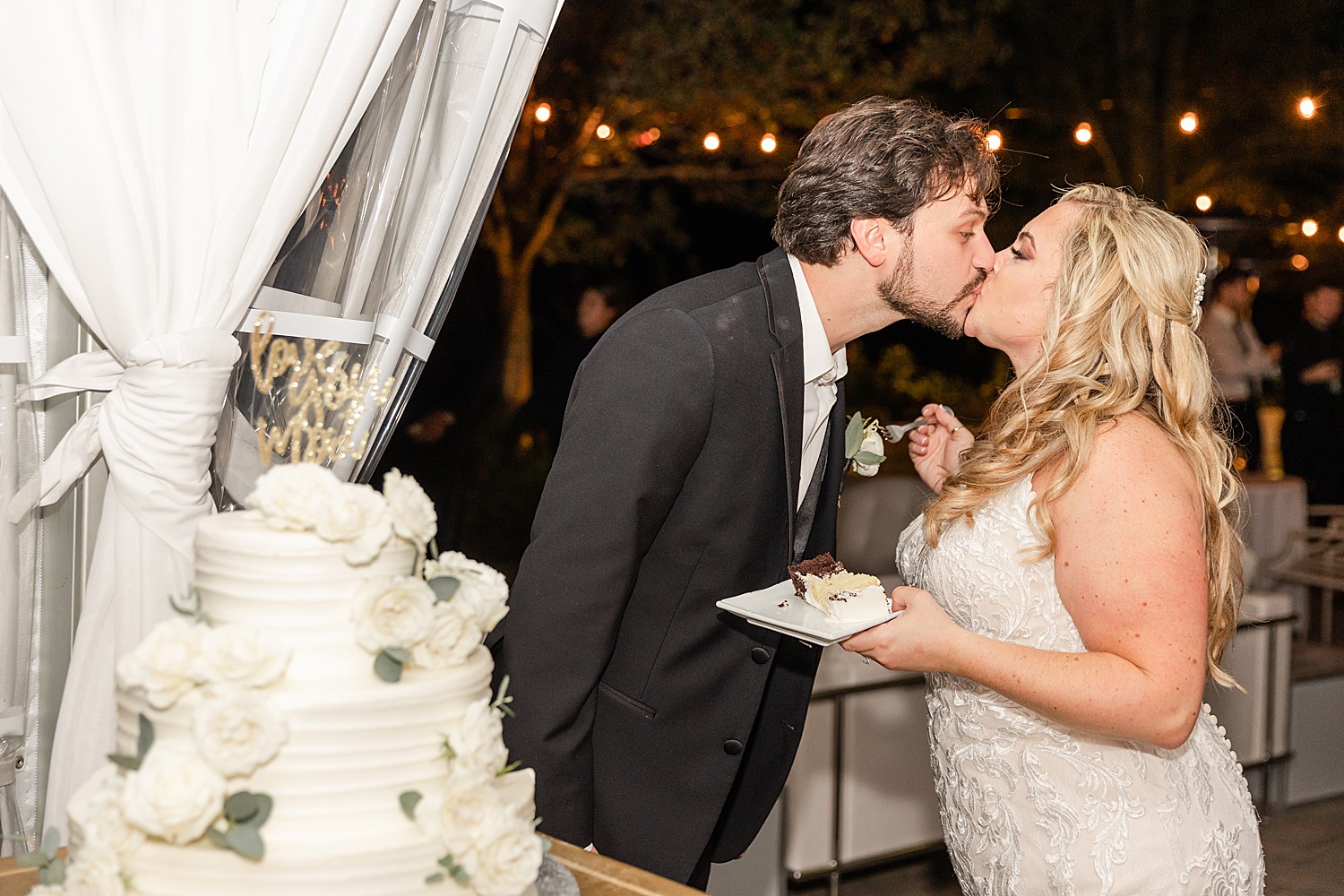 couple kiss after cutting their wedding cake at reception