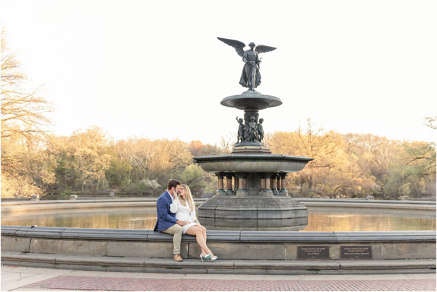 couple sitting on waters edge at a fountain in central park 