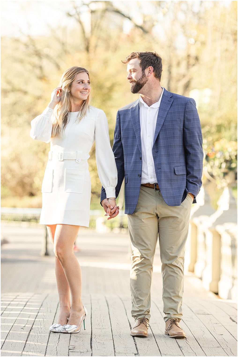 couple look at each other as they walk across central park bridge
