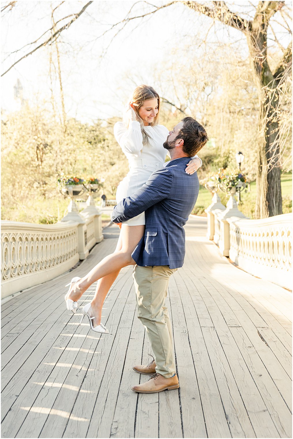man lifts his fiance up in the middle of a bridge in NYC engagement session