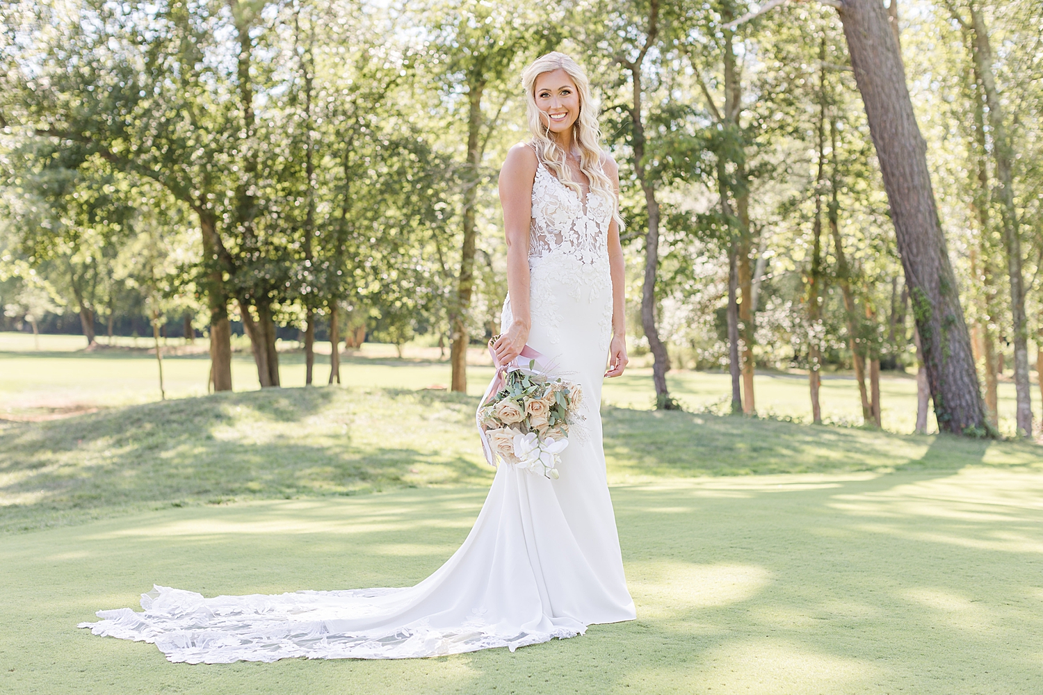 bride stands on golf course holding bouquet