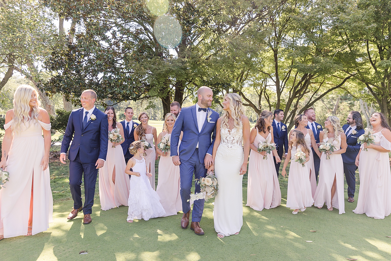 bride and groom walk together with wedding party behind 