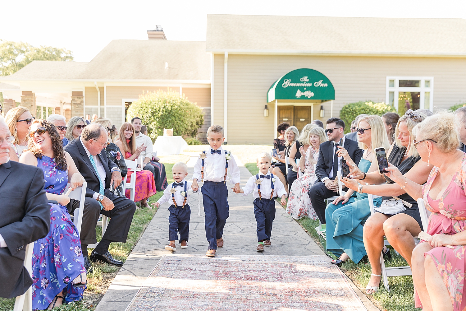 ring bearers come down the aisle at outdoor wedding ceremony