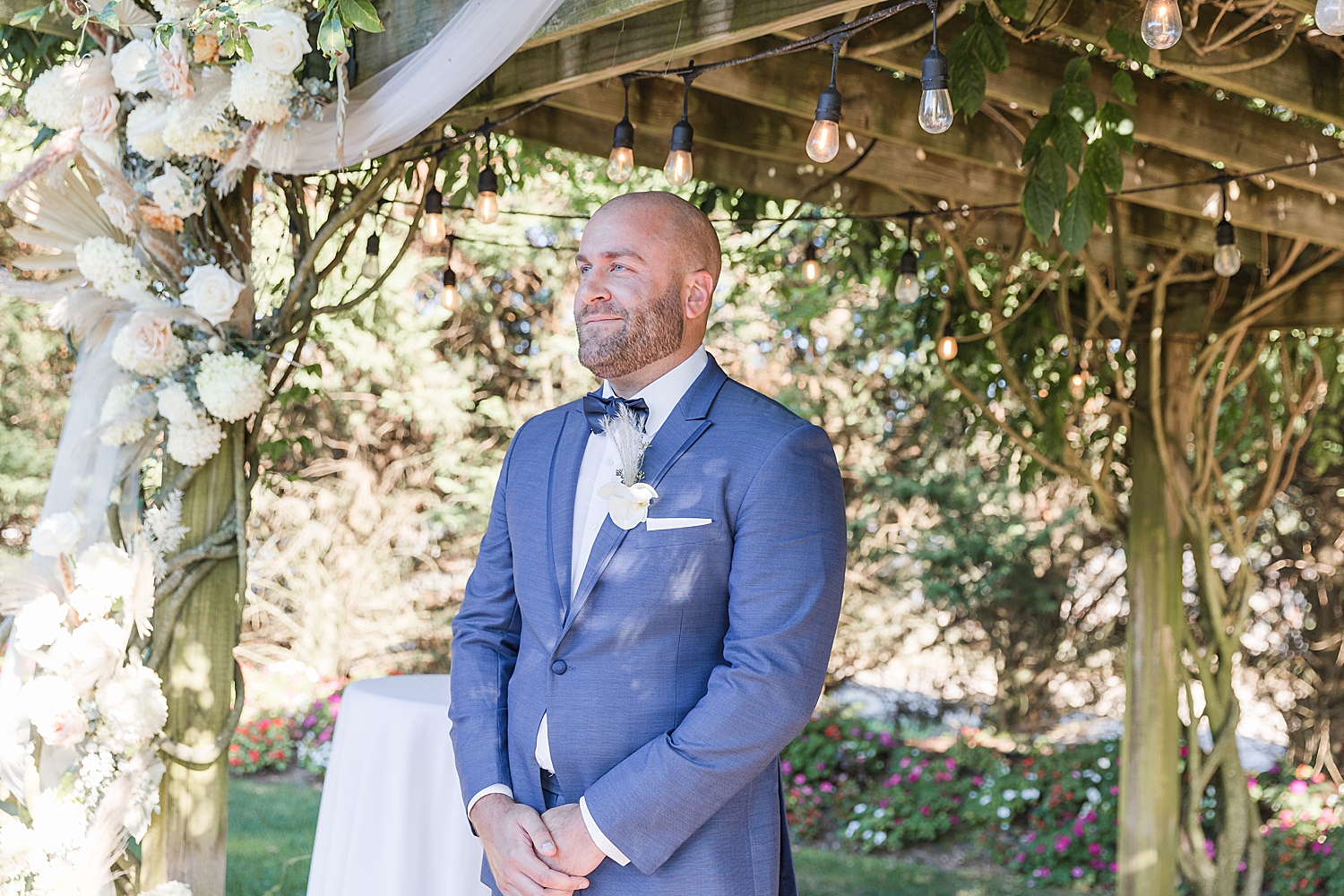 groom smiles as he watches his bride walk towards him