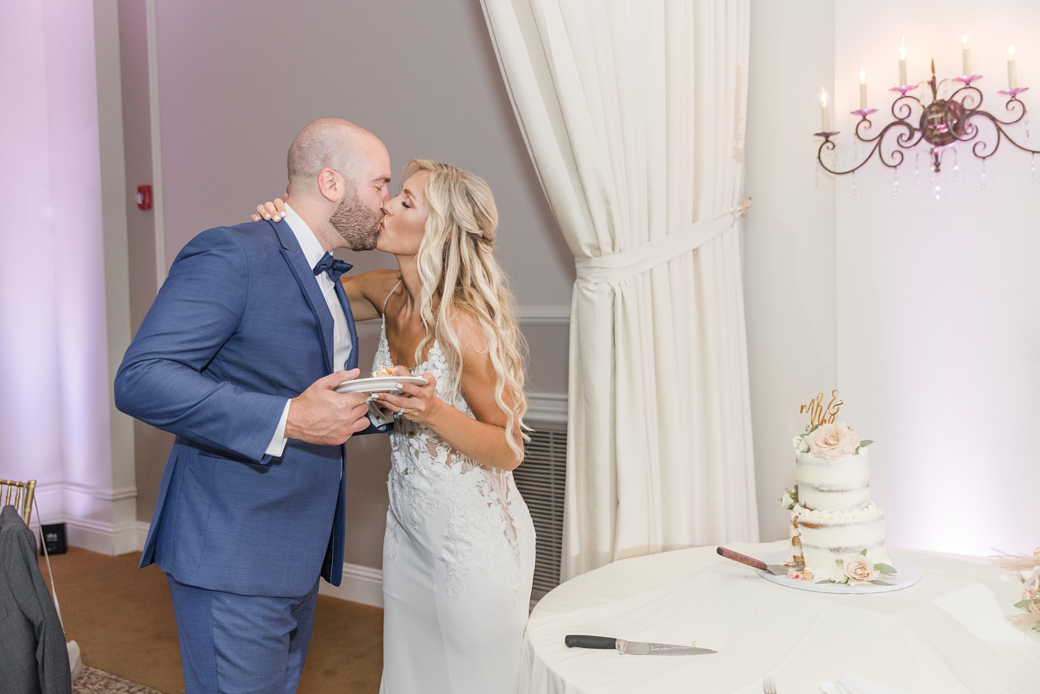 couple kiss as they eat their wedding cake at Boho Inspired Summer Wedding at Eastlyn Golf Course