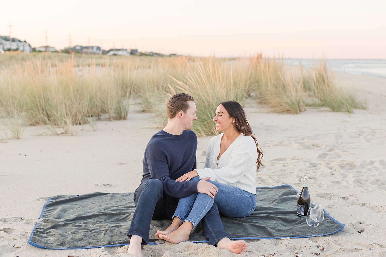 couple sit together on blanket at the beach