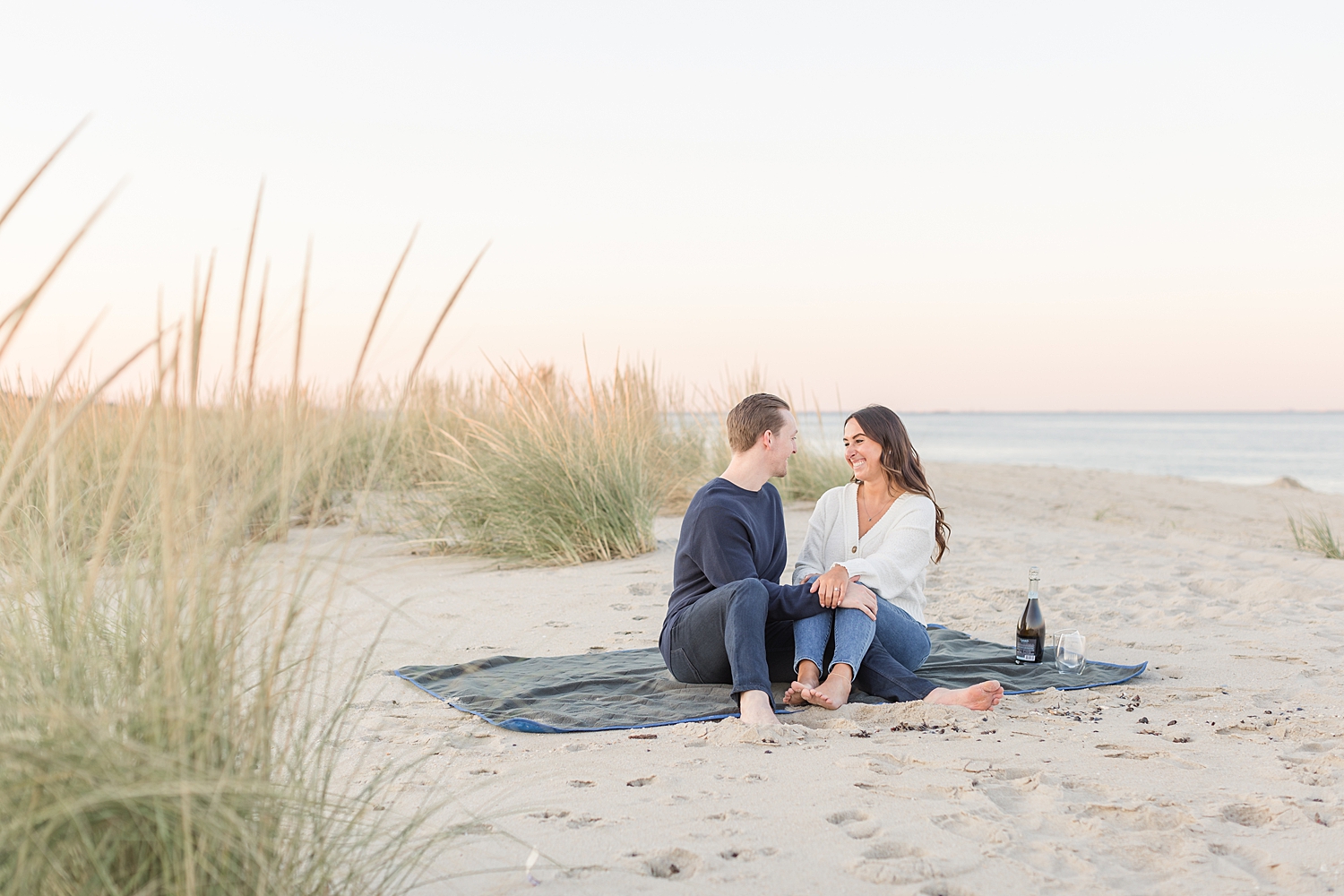 Romantic beach engagement photos of couple sitting together at the beach