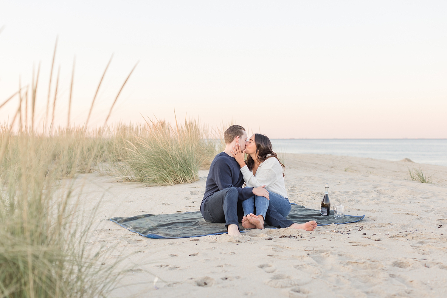 couple kiss as they sit on the beach