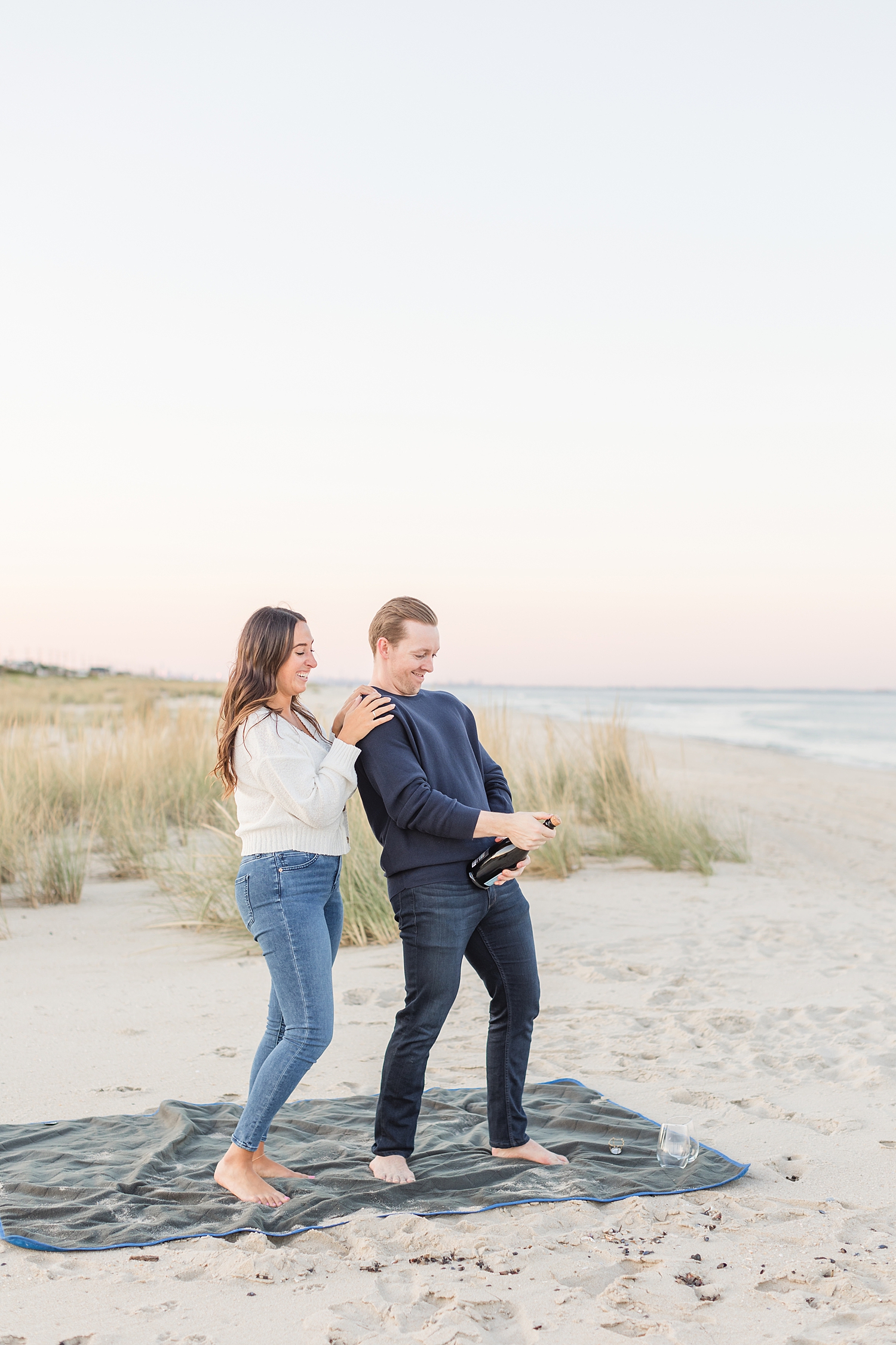 candid engagement photo of couple opening champagne bottle