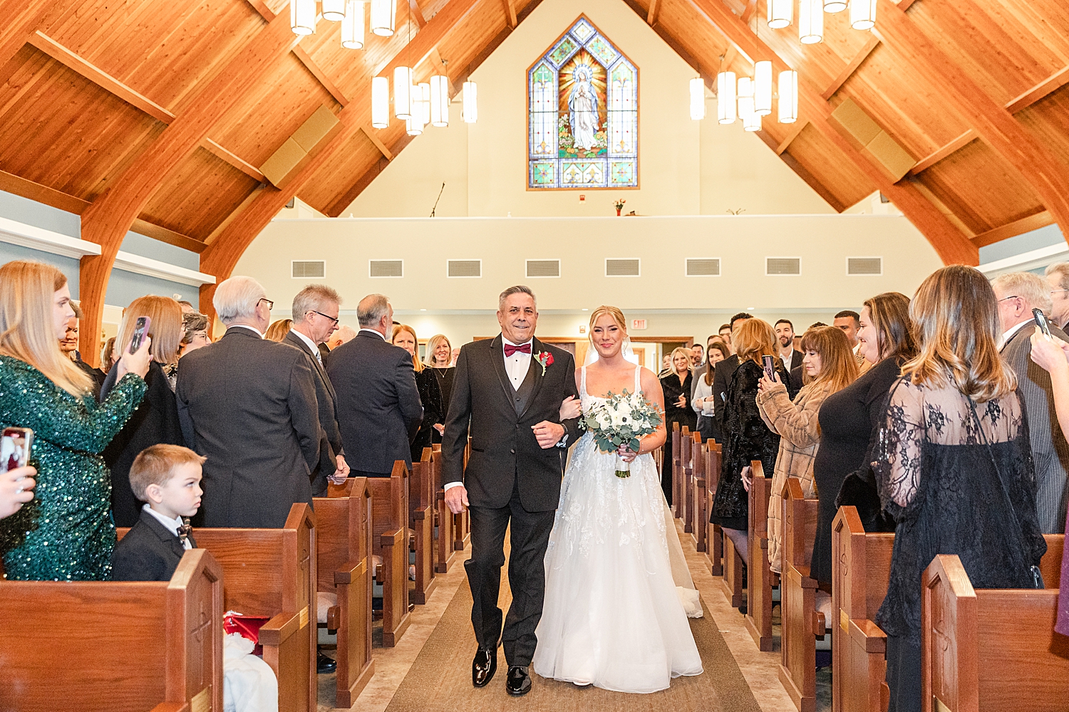 bride and father walk down the aisle together at wedding ceremony