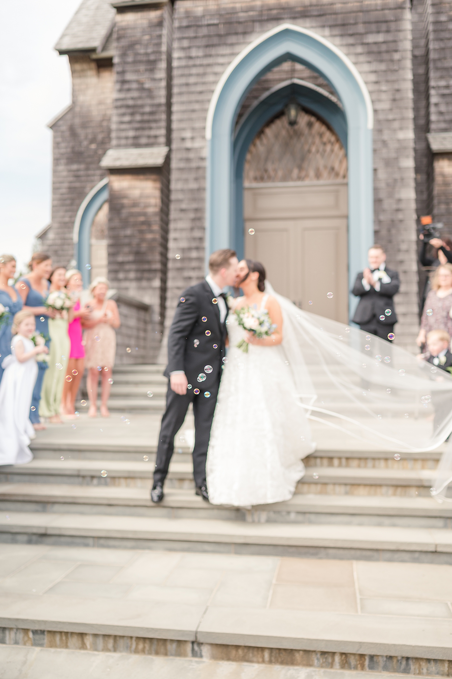 Newlyweds kiss as bubble surround them during wedding exit