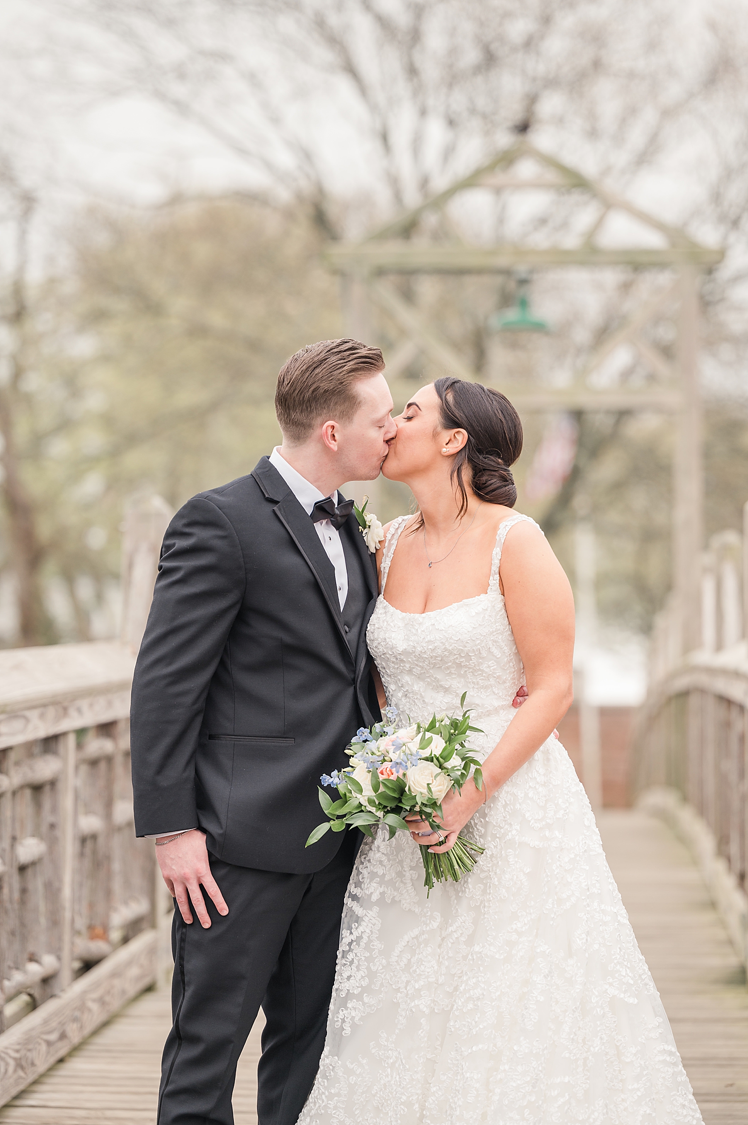 Newlyweds kiss on wooden bridge from Romantic Spring Wedding in New Jersey