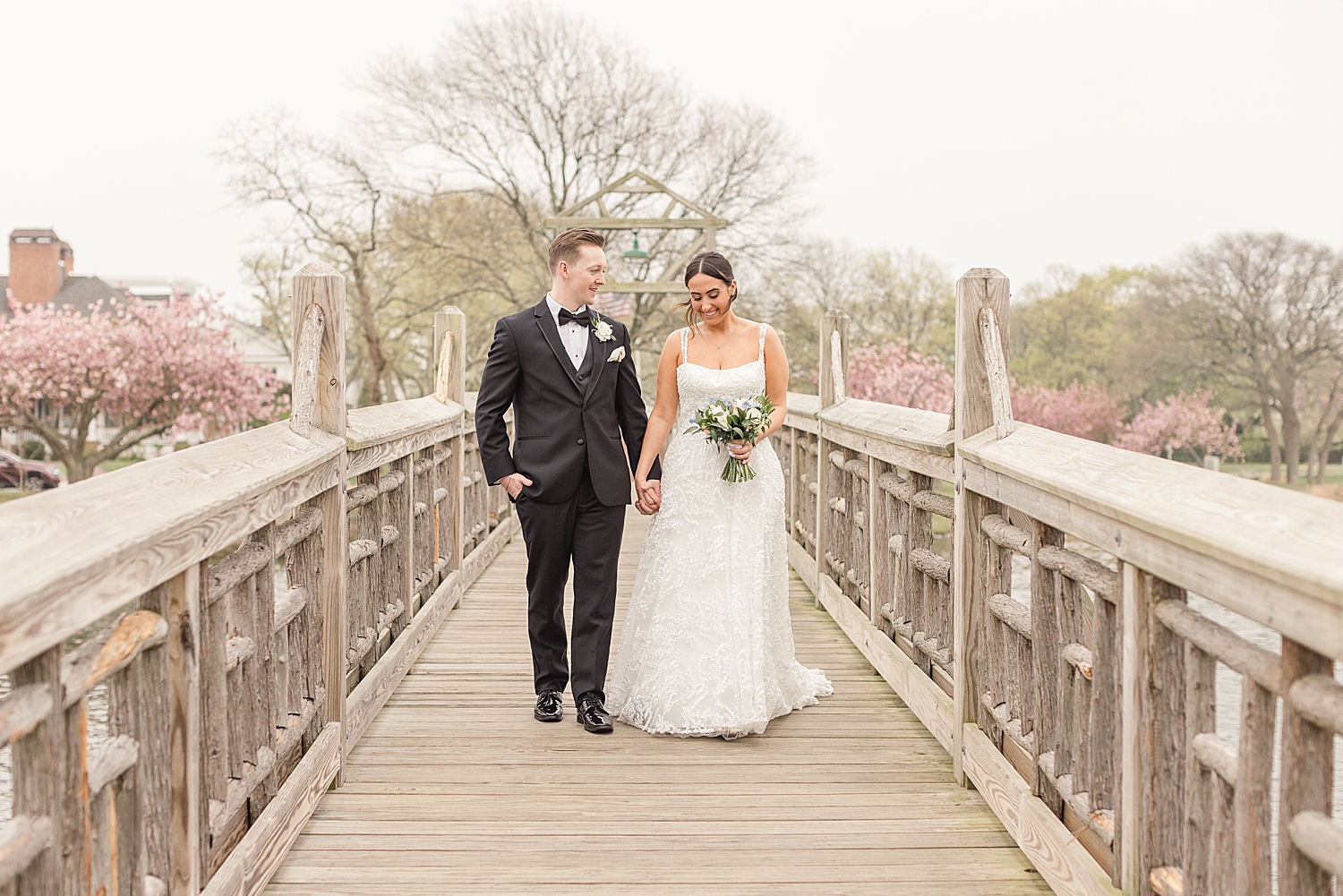 couple walk together holding hands on wooden bridge 