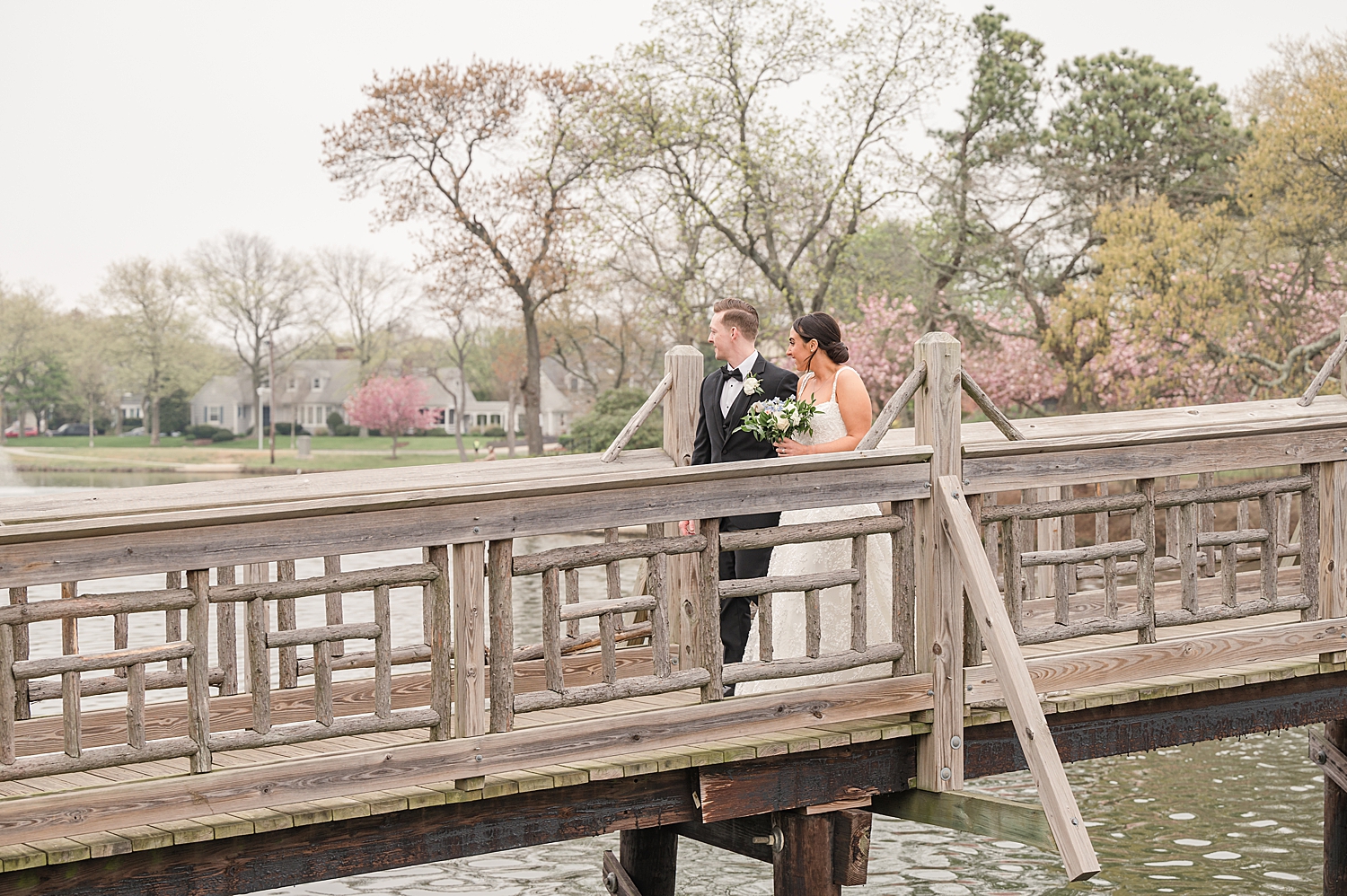 couple hold hands on wooden bridge in Spring Lake Devine Park in New Jersey 