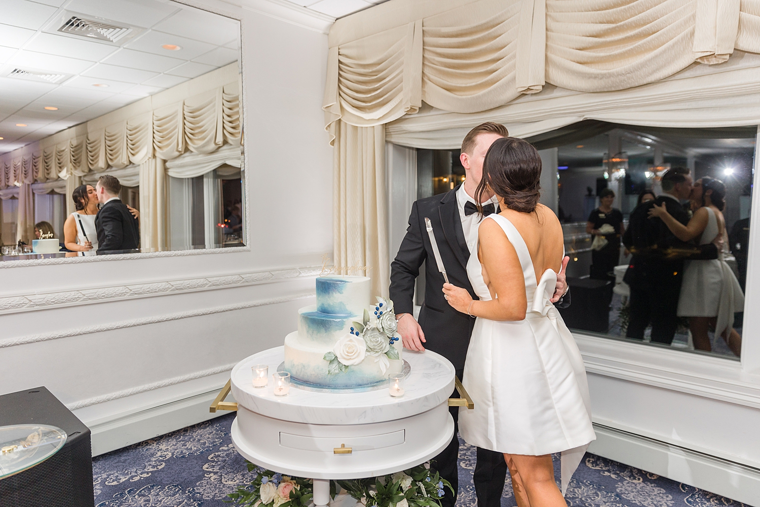 newlyweds kiss as they cut the wedding cake